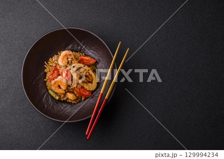 Rice and prawns or paella, a meal with seafood and vegetables. Cooked rice with shrimp Rice and prawns or paella, a meal with seafood and vegetables. Cooked rice with shrimp 129994234