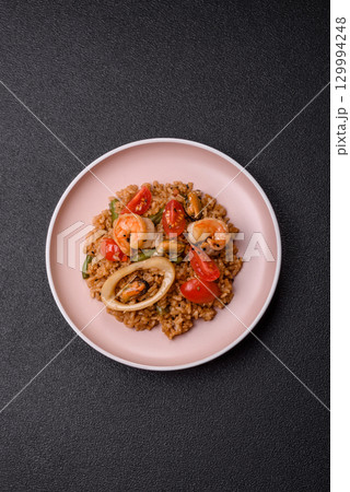Rice and prawns or paella, a meal with seafood and vegetables. Cooked rice with shrimp Rice and prawns or paella, a meal with seafood and vegetables. Cooked rice with shrimp 129994248