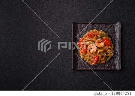 Rice and prawns or paella, a meal with seafood and vegetables. Cooked rice with shrimp 129994251
