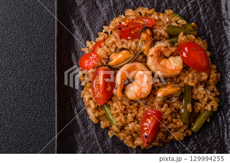 Rice and prawns or paella, a meal with seafood and vegetables. Cooked rice with shrimp 129994255