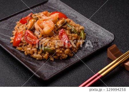 Rice and prawns or paella, a meal with seafood and vegetables. Cooked rice with shrimp 129994258