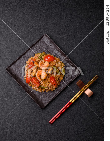 Rice and prawns or paella, a meal with seafood and vegetables. Cooked rice with shrimp 129994264