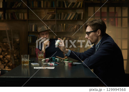 An intense card game between two players in smoky library 129994568