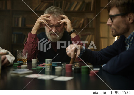 An intense poker game in a vintage library featuring men company 129994580