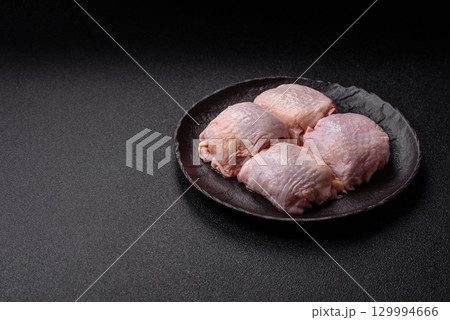 Meat, raw chicken thigh, leg in skin with salt and spices. Raw chicken thigh 129994666