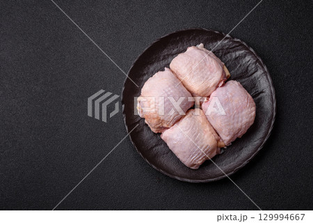 Meat, raw chicken thigh, leg in skin with salt and spices. Raw chicken thigh 129994667