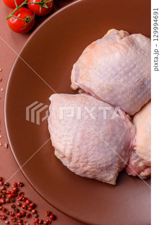 Meat, raw chicken thigh, leg in skin with salt and spices. Raw chicken thigh 129994691