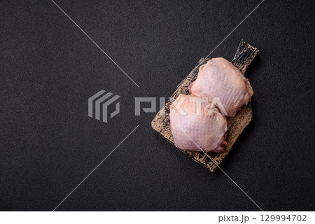 Meat, raw chicken thigh, leg in skin with salt and spices. Raw chicken thigh 129994702