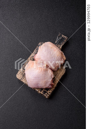 Meat, raw chicken thigh, leg in skin with salt and spices. Raw chicken thigh 129994703