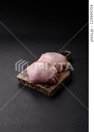 Meat, raw chicken thigh, leg in skin with salt and spices. Raw chicken thigh 129994704