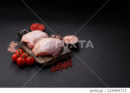 Meat, raw chicken thigh, leg in skin with salt and spices. Raw chicken thigh Meat, raw chicken thigh, leg in skin with salt and spices. Raw chicken thigh 129994713