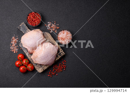 Meat, raw chicken thigh, leg in skin with salt and spices. Raw chicken thigh Meat, raw chicken thigh, leg in skin with salt and spices. Raw chicken thigh 129994714
