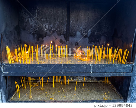 Burning candles placed in a metal holder inside a church. Faith, spirituality, devotion and religious tradition in sacred ritual. Burning candles placed in a metal holder inside a church. Faith, spirituality, devotion and religious tradition in sacred ritual. 129994842