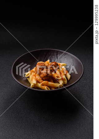 Penne pasta with meatballs in tomato sauce with salt and spices. Italian food penne pasta 129995238