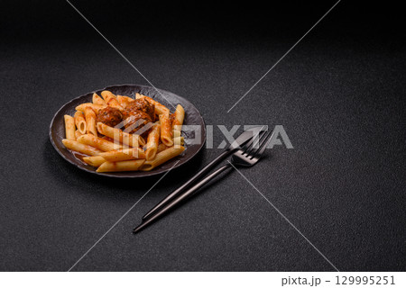 Penne pasta with meatballs in tomato sauce with salt and spices. Italian food penne pasta 129995251