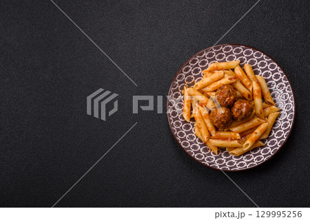 Penne pasta with meatballs in tomato sauce with salt and spices. Italian food penne pasta 129995256