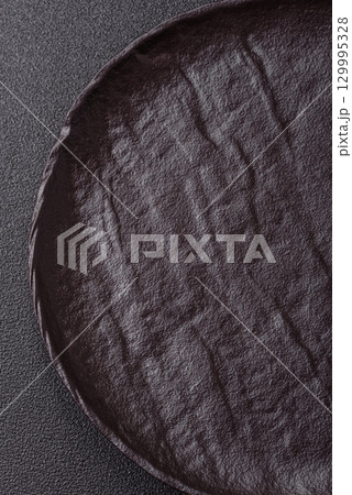 Empty round black plate for food, risotto or pasta. Empty plate on dark background Empty round black plate for food, risotto or pasta. Empty plate on dark background 129995328