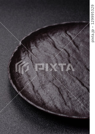 Empty round black plate for food, risotto or pasta. Empty plate on dark background Empty round black plate for food, risotto or pasta. Empty plate on dark background 129995329