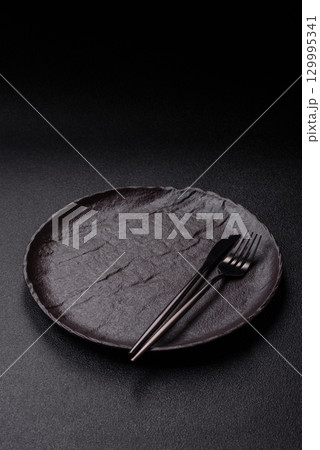 Empty round black plate for food, risotto or pasta. Empty plate on dark background Empty round black plate for food, risotto or pasta. Empty plate on dark background 129995341