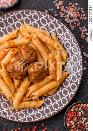 Penne pasta with meatballs in tomato sauce with salt and spices. Italian food penne pasta 129995354