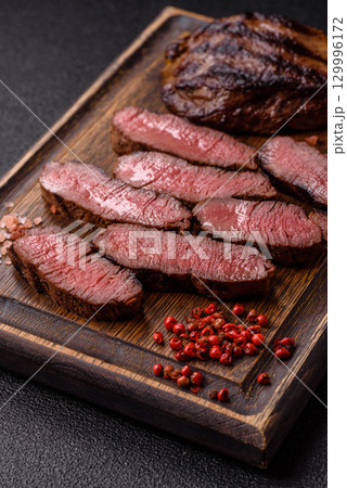 Grilled beef steak meat with salt and pepper. Beef steak grilled on a barbecue Grilled beef steak meat with salt and pepper. Beef steak grilled on a barbecue 129996172