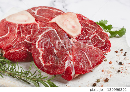 knuckle on the bone, raw meat for ossobuco, on a wooden chopping board, with a sprig of rosemary, and spices, top view, no people, knuckle on the bone, raw meat for ossobuco, on a wooden chopping board, with a sprig of rosemary, and spices, top view, no people, 129996292