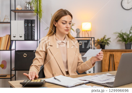 Businesswoman sorts receipts uses calculator balances budget signs final contract with pleased smile 129996696