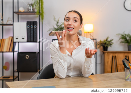Young businesswoman records voice message states argument and listens to reply on smartphone speaker Young businesswoman records voice message states argument and listens to reply on smartphone speaker 129996735