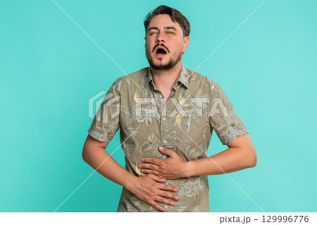 Man clutching stomach bending forward with painful expression showing sudden abdominal discomfort 129996776