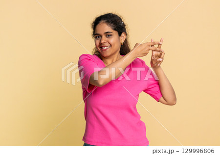 Indian woman gesturing hashtag symbol with fingers, playfully suggesting social media topic 129996806