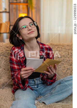 Woman writing heartfelt letter on paper at home, smiling with emotion before sealing it in envelope Woman writing heartfelt letter on paper at home, smiling with emotion before sealing it in envelope 129996818