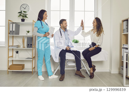 Doctor giving high five with a young happy woman patient in medical clinic. Doctor giving high five with a young happy woman patient in medical clinic. 129996839