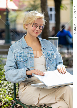 European young woman freelancer in city street closes laptop screen finishing working online job European young woman freelancer in city street closes laptop screen finishing working online job 129997148