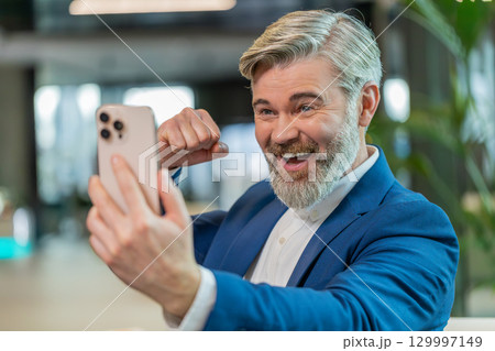 Amazed businessman using smartphone shocked by sudden victory lottery win in modern office lobby Amazed businessman using smartphone shocked by sudden victory lottery win in modern office lobby 129997149
