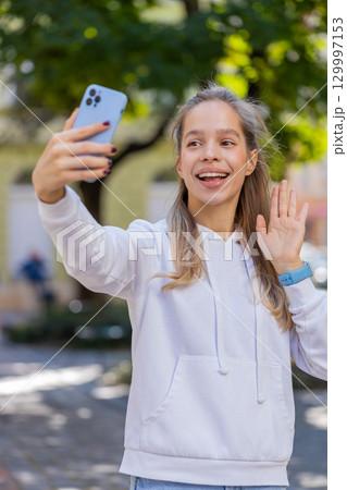 Caucasian young woman girl tourist talking video chat chatting phone call smartphone on city street 129997153