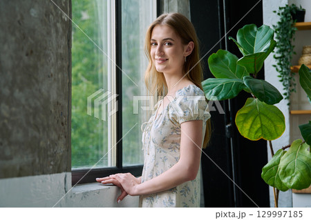 Young beautiful smiling romantic girl looking at camera, standing near window 129997185