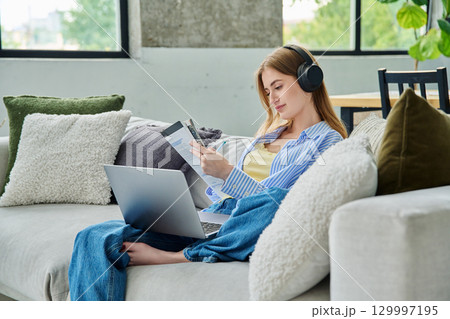 Young teen girl student in headphones with laptop textbook watching video lesson at home 129997195