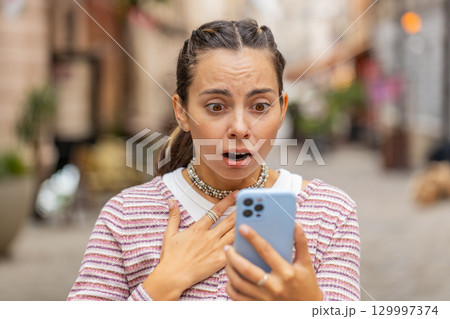 Woman using smartphone shock sudden lottery results bad news fortune loss app fail virus thief fraud 129997374