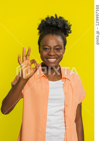 African American woman giving OK sign, slight smile positivity, confident gesture approval vibe 129997388