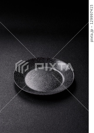 Empty round black plate for food, kitchen utensils on dining table. Empty plate 129997415