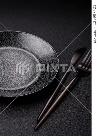Empty round black plate for food, kitchen utensils on dining table. Empty plate Empty round black plate for food, kitchen utensils on dining table. Empty plate 129997423