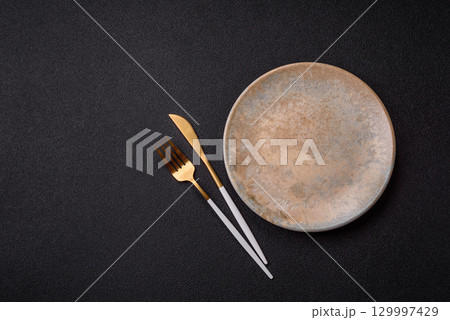 Empty round black plate for food, kitchen utensils on dining table. Empty plate Empty round black plate for food, kitchen utensils on dining table. Empty plate 129997429