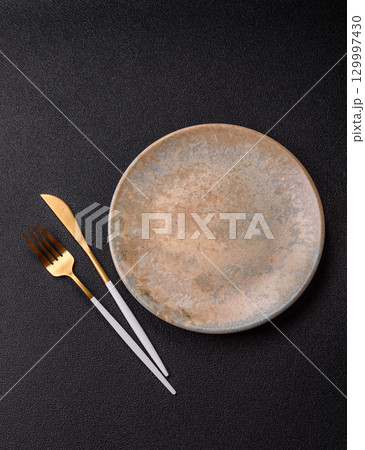 Empty round black plate for food, kitchen utensils on dining table. Empty plate Empty round black plate for food, kitchen utensils on dining table. Empty plate 129997430