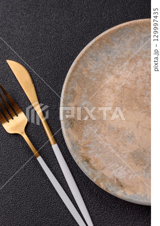 Empty round black plate for food, kitchen utensils on dining table. Empty plate Empty round black plate for food, kitchen utensils on dining table. Empty plate 129997435