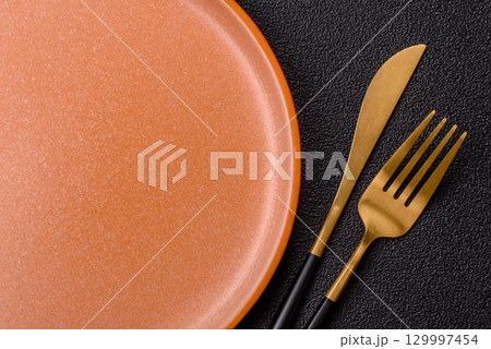 Empty round black plate for food, kitchen utensils on dining table. Empty plate Empty round black plate for food, kitchen utensils on dining table. Empty plate 129997454