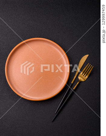 Empty round black plate for food, kitchen utensils on dining table. Empty plate Empty round black plate for food, kitchen utensils on dining table. Empty plate 129997459