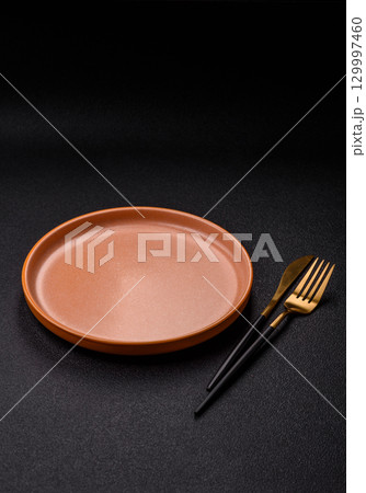 Empty round black plate for food, kitchen utensils on dining table. Empty plate Empty round black plate for food, kitchen utensils on dining table. Empty plate 129997460