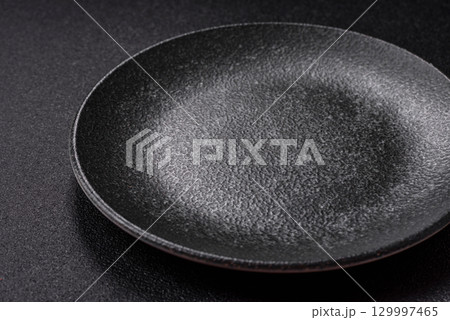 Empty round black plate for food, kitchen utensils on dining table. Empty plate Empty round black plate for food, kitchen utensils on dining table. Empty plate 129997465