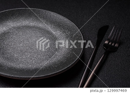 Empty round black plate for food, kitchen utensils on dining table. Empty plate Empty round black plate for food, kitchen utensils on dining table. Empty plate 129997469