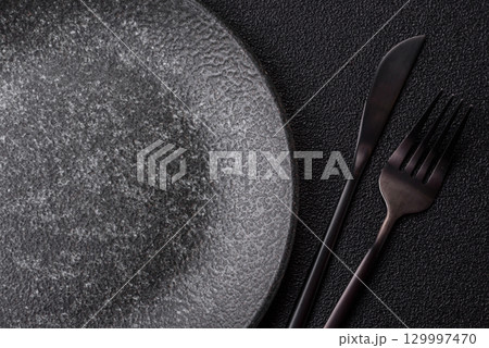 Empty round black plate for food, kitchen utensils on dining table. Empty plate Empty round black plate for food, kitchen utensils on dining table. Empty plate 129997470